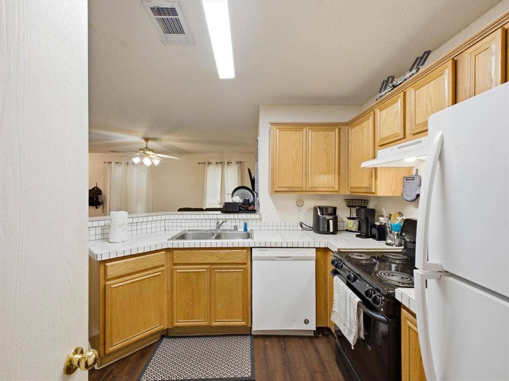 2001 Waleska Plaza, Dallas, TX 75211 Kitchen featuring wood-finish cabinetry, white appliances, and a tile backsplash