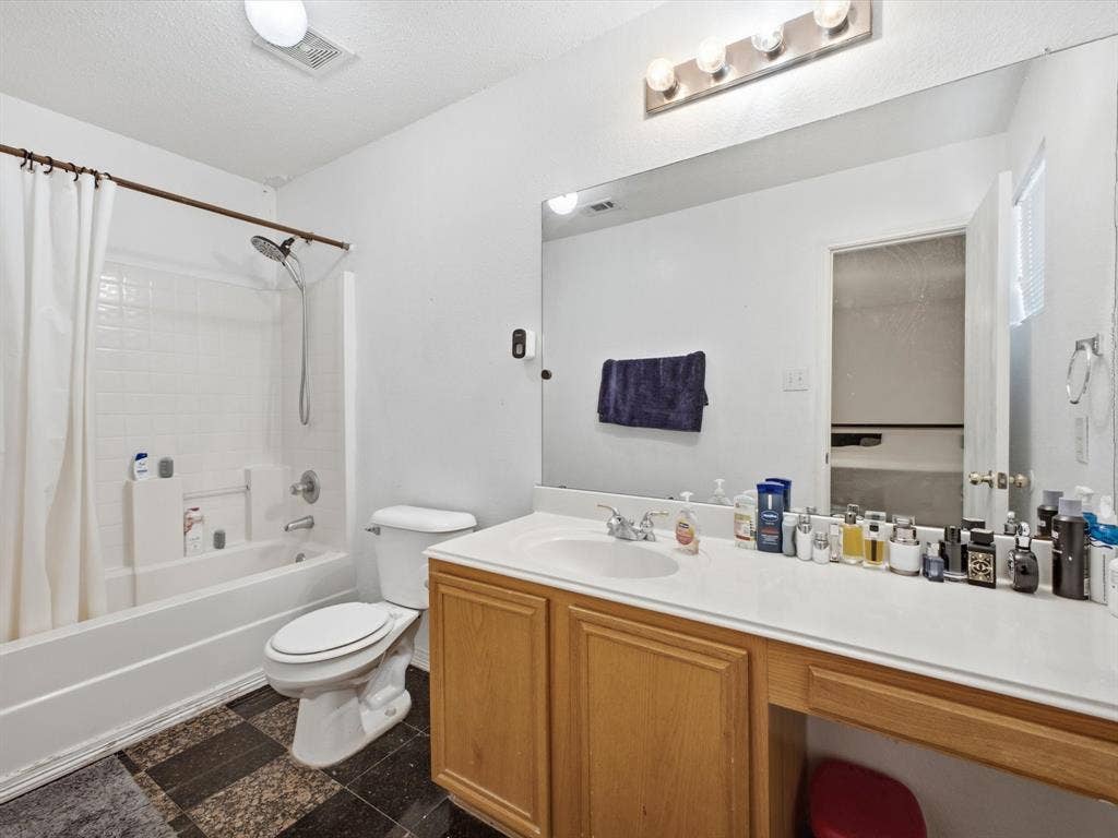 2001 Waleska Plaza, Dallas, TX 75211 Tub and shower combination with white subway tile surround, single vanity with wood-finish cabinetry, and an integrated countertop with a single sink