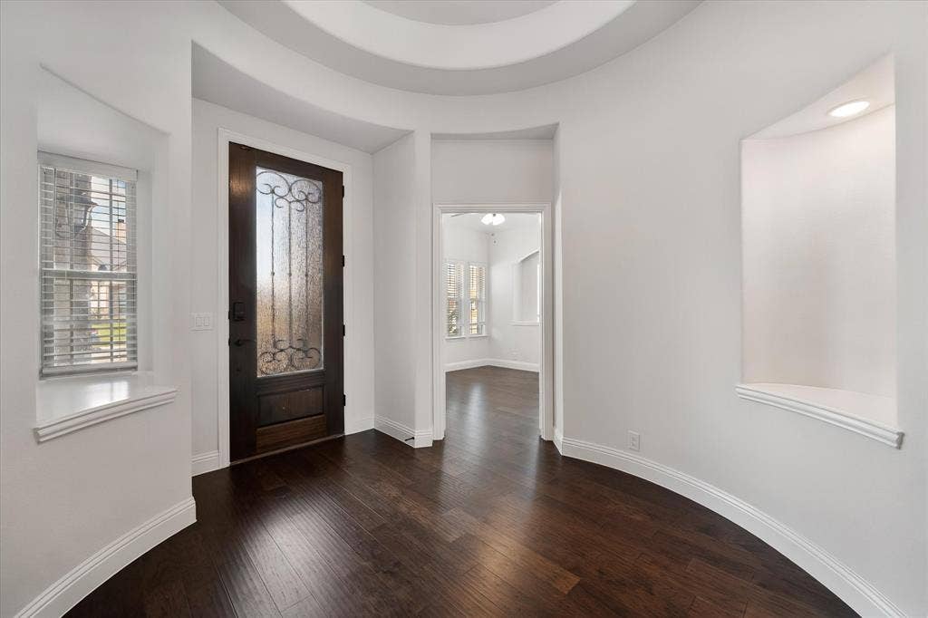 5626 Rutherford Drive, Midlothian, TX 76065 This is the moment you walk in the front door — feel that curved wall? It's such a unique architectural detail, and the dark wood floors set the tone right away for the whole downstairs.