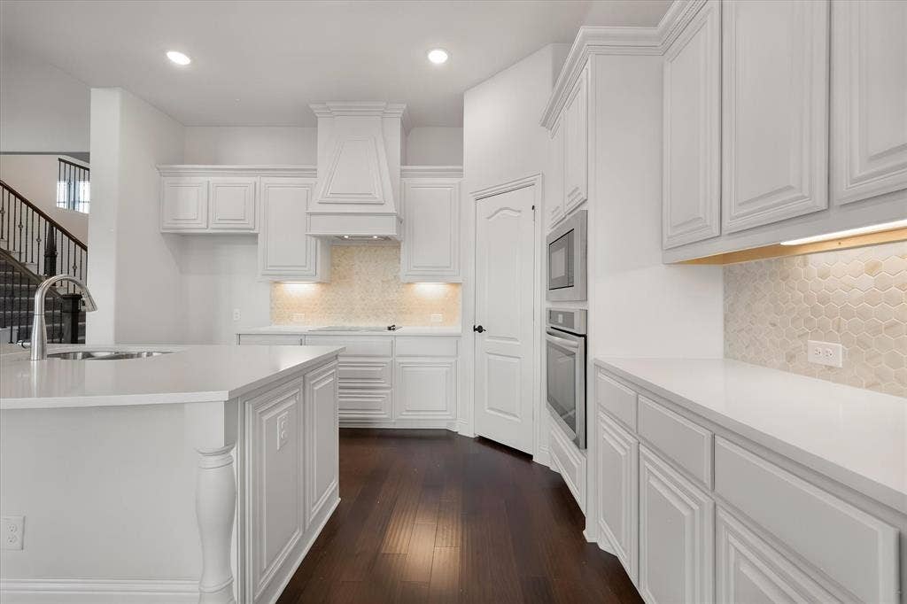 5626 Rutherford Drive, Midlothian, TX 76065 This angle shows off the full run of cabinetry — the vent hood, the built-in oven and microwave, and the hexagon tile backsplash adds just the right amount of texture.