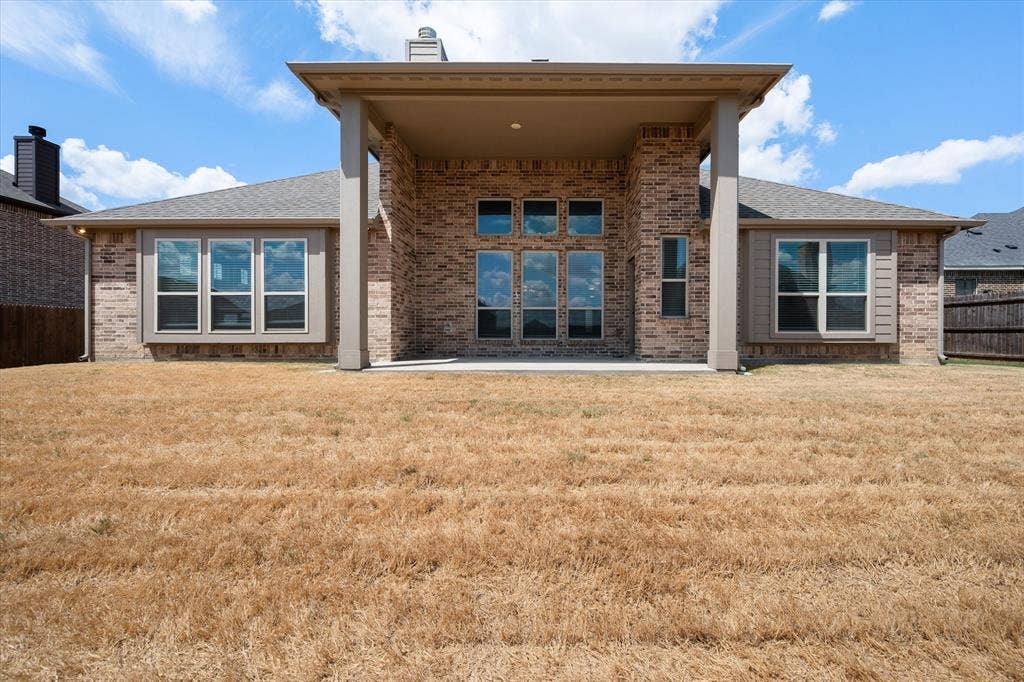 5626 Rutherford Drive, Midlothian, TX 76065 Stepping back to take in the whole rear of the home — the tall, covered patio and big windows make such a statement from the yard.
