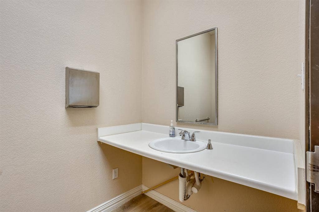 1415 E Belt Line Road, Carrollton, TX 75006 Wall-mounted rectangular mirror positioned above a spacious countertop with an integrated white sink