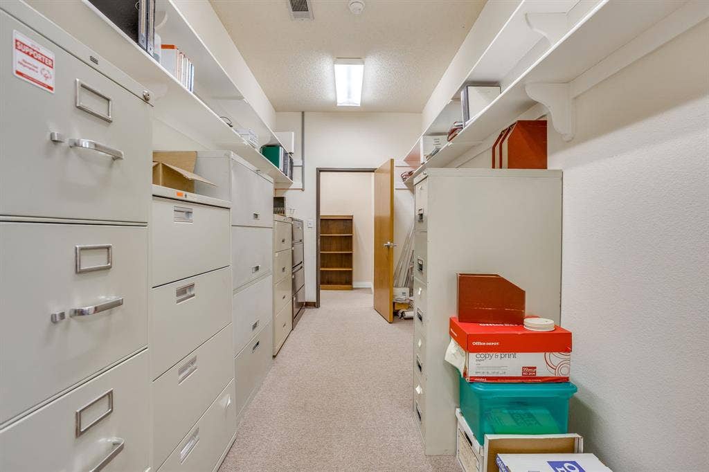 1415 E Belt Line Road, Carrollton, TX 75006 Recessed lighting illuminates the carpeted corridor, featuring built-in shelving and a doorway with a visible wooden frame