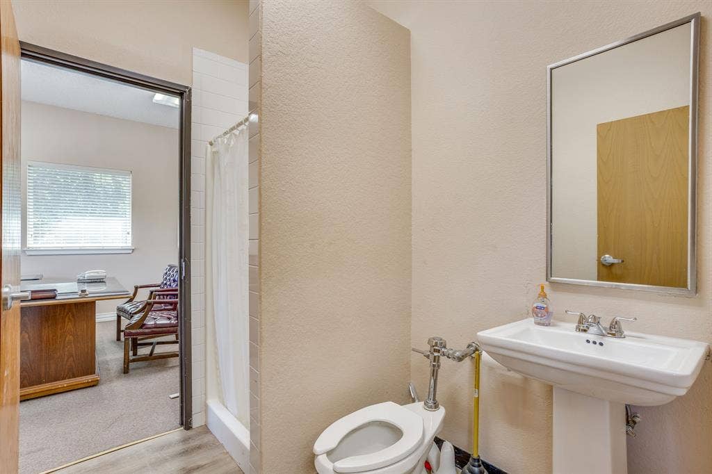 1415 E Belt Line Road, Carrollton, TX 75006 Bathroom with a pedestal sink, wall-mounted mirror, and white tiled shower stall