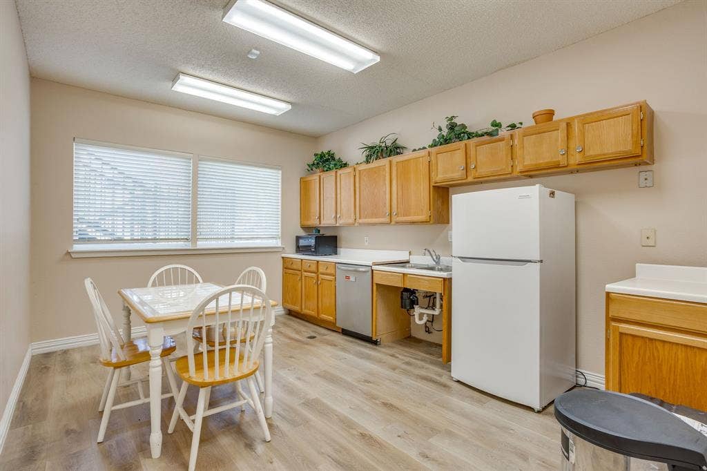 1415 E Belt Line Road, Carrollton, TX 75006 Kitchen area featuring wood-finish flooring, overhead fluorescent lighting, and two windows with blinds