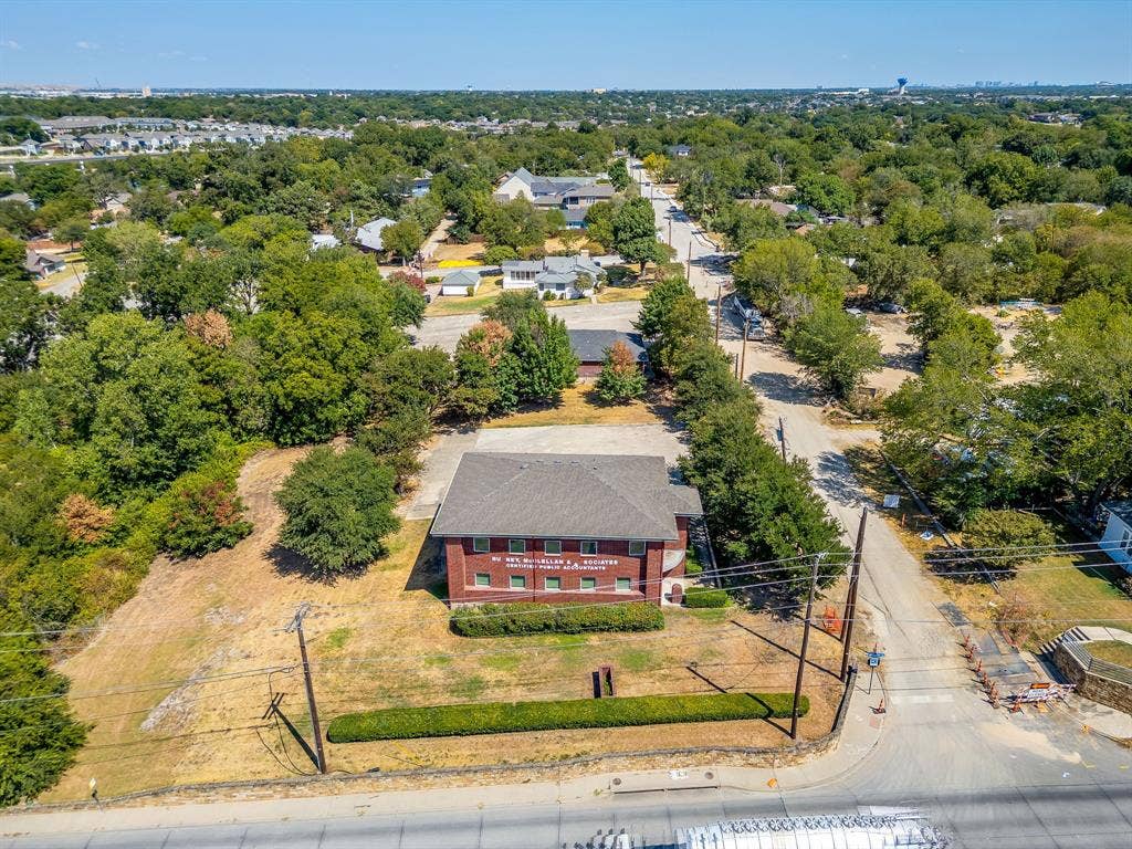 1415 E Belt Line Road, Carrollton, TX 75006 Brick building with a dark shingle roof, surrounded by mature trees and a manicured hedge