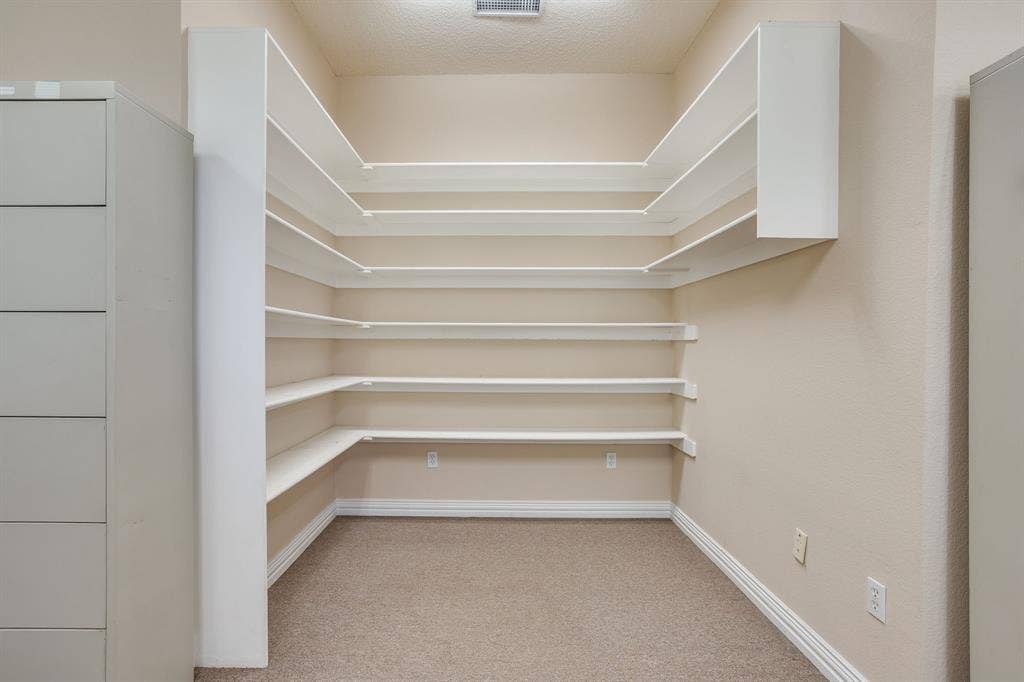 1415 E Belt Line Road, Carrollton, TX 75006 Wall-to-wall shelving with multiple tiers, built-in cabinetry, and carpet flooring