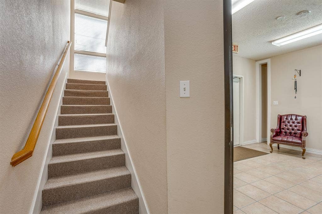 1415 E Belt Line Road, Carrollton, TX 75006 Carpeted staircase with wood handrail, upper-level window, and adjacent tiled flooring