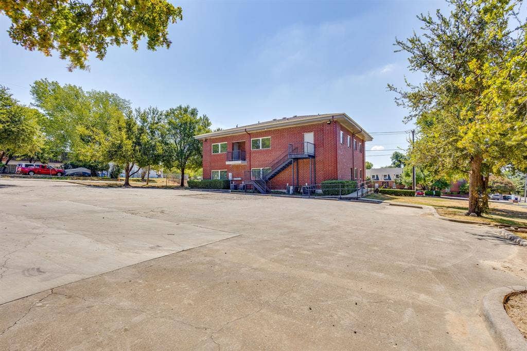 1415 E Belt Line Road, Carrollton, TX 75006 Brick exterior building with multiple windows, second-story balcony with metal railing, and exterior staircase