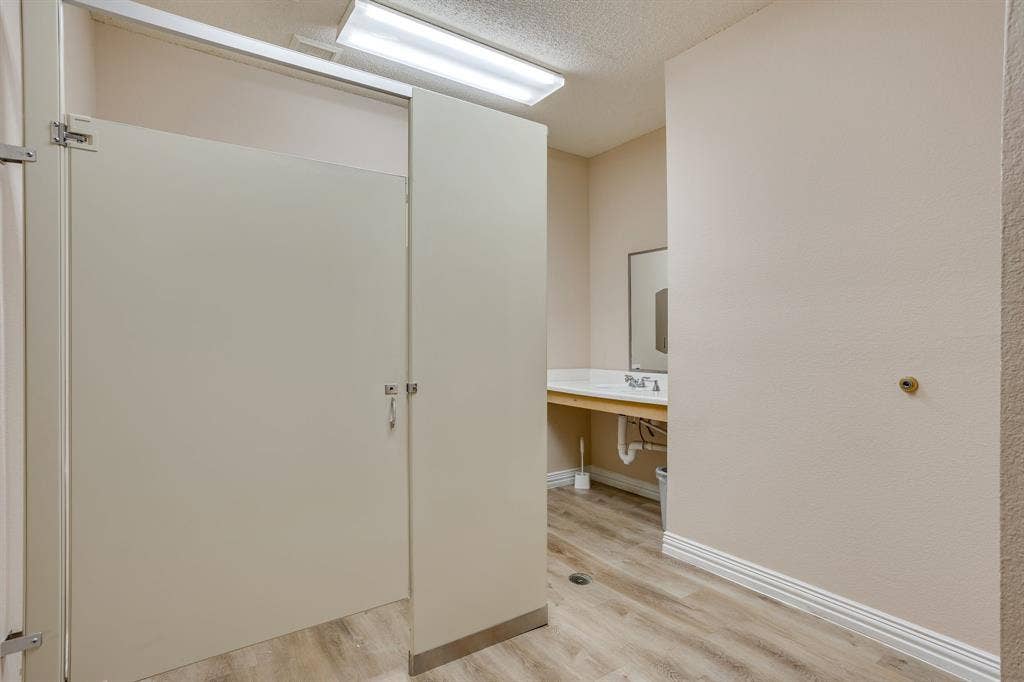 1415 E Belt Line Road, Carrollton, TX 75006 Restroom featuring wood-finish flooring, a vanity with a drop-in sink, and a wall-mounted mirror