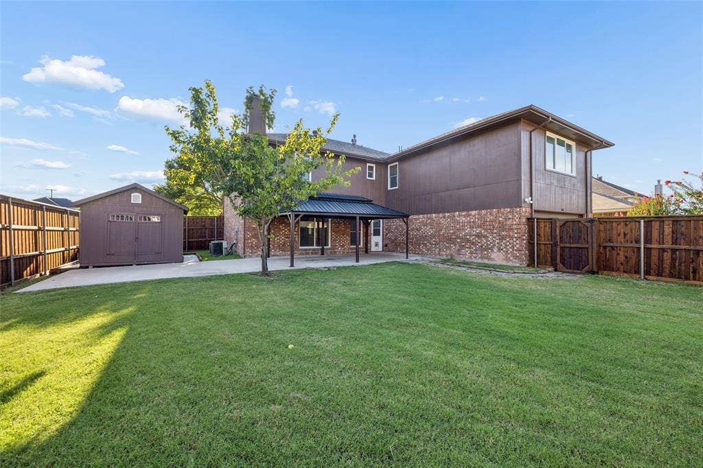 753 Summerfield Drive, Allen, TX 75002 Spacious backyard featuring a covered patio, expansive lawn, and a detached storage shed
