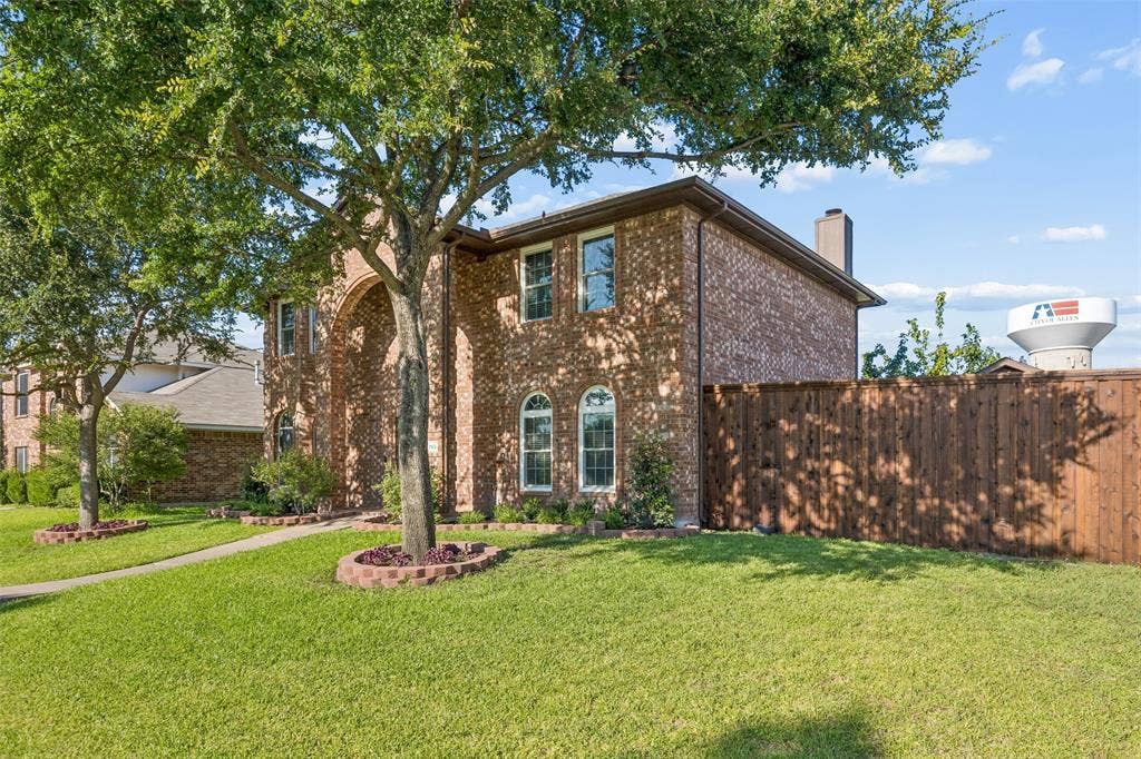 753 Summerfield Drive, Allen, TX 75002 Brick exterior with arched entryway, multiple windows, established trees, and a privacy fence