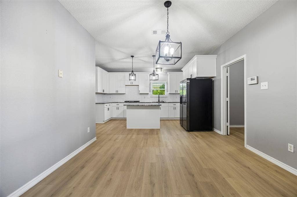 753 Summerfield Drive, Allen, TX 75002 Wood-finish flooring, white cabinetry, island with countertop, black appliances, and pendant lighting