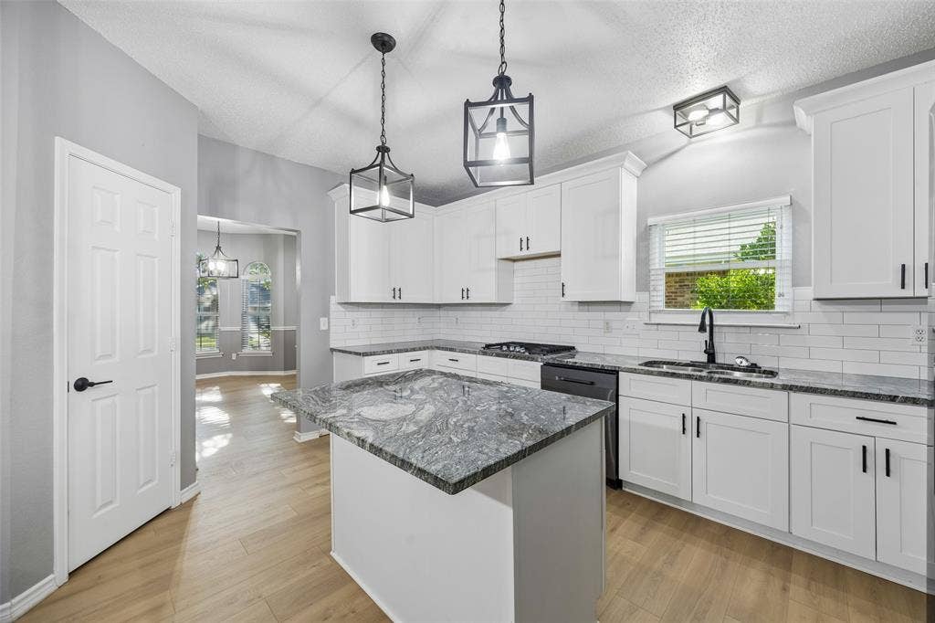 753 Summerfield Drive, Allen, TX 75002 Kitchen featuring white shaker-style cabinetry, black hardware, subway tile backsplash, and a central island with a stone countertop