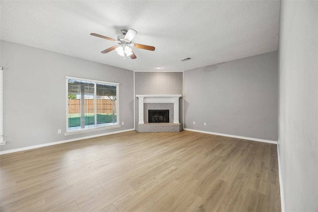753 Summerfield Drive, Allen, TX 75002 Wood-finish flooring, corner fireplace with a white mantel, ceiling fan with light fixture, and a sliding glass door