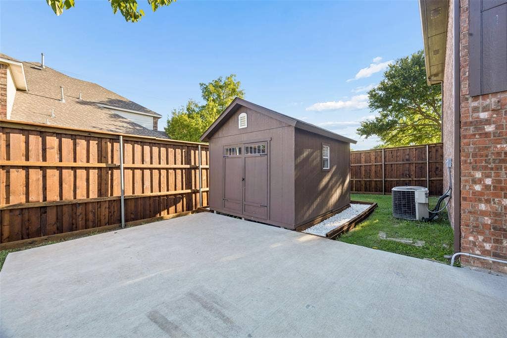 753 Summerfield Drive, Allen, TX 75002 Concrete patio with a detached storage shed, wood privacy fencing, and a brick exterior wall