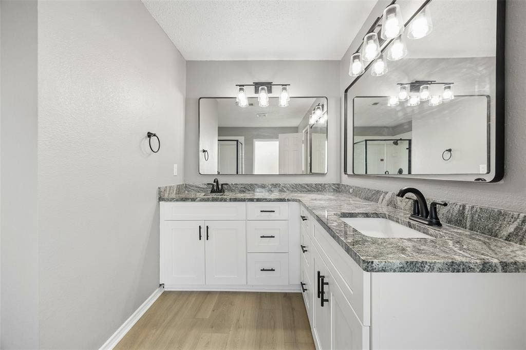 753 Summerfield Drive, Allen, TX 75002 Dual vanity with granite countertops, white cabinetry, undermount sinks, matte black hardware, and wood-finish flooring