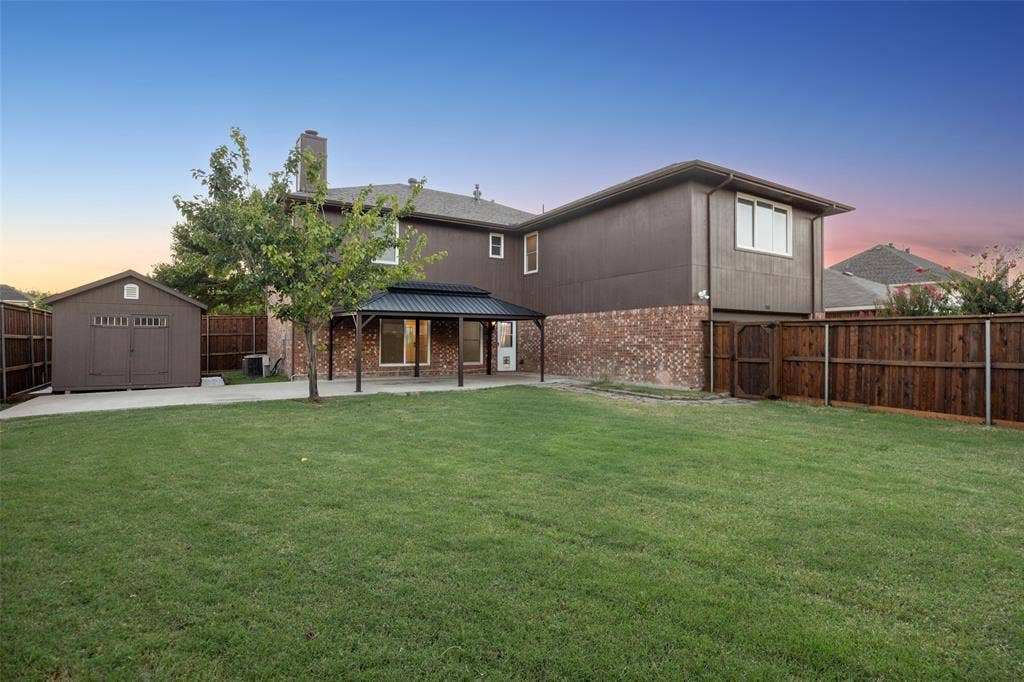753 Summerfield Drive, Allen, TX 75002 Expansive green lawn with a covered patio, wood privacy fencing, and a detached storage shed