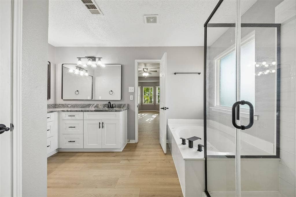 753 Summerfield Drive, Allen, TX 75002 Dual vanity with granite-style countertop, white cabinetry, wood-finish flooring, and a glass-enclosed shower