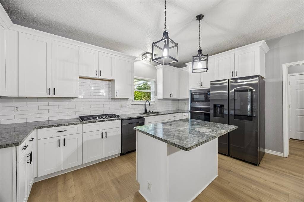 753 Summerfield Drive, Allen, TX 75002 Kitchen featuring white shaker cabinets, subway tile backsplash, dark-toned appliances, and a central island with a stone-finish countertop