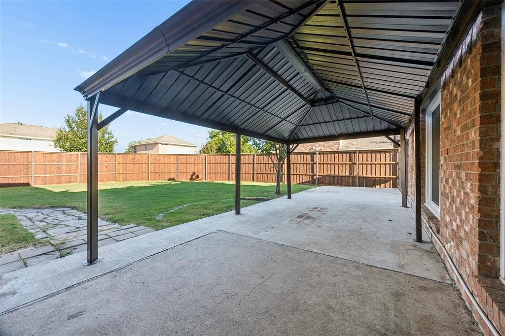 753 Summerfield Drive, Allen, TX 75002 Expansive covered patio with steel beam construction and corrugated metal roof, offering generous shelter over a concrete foundation