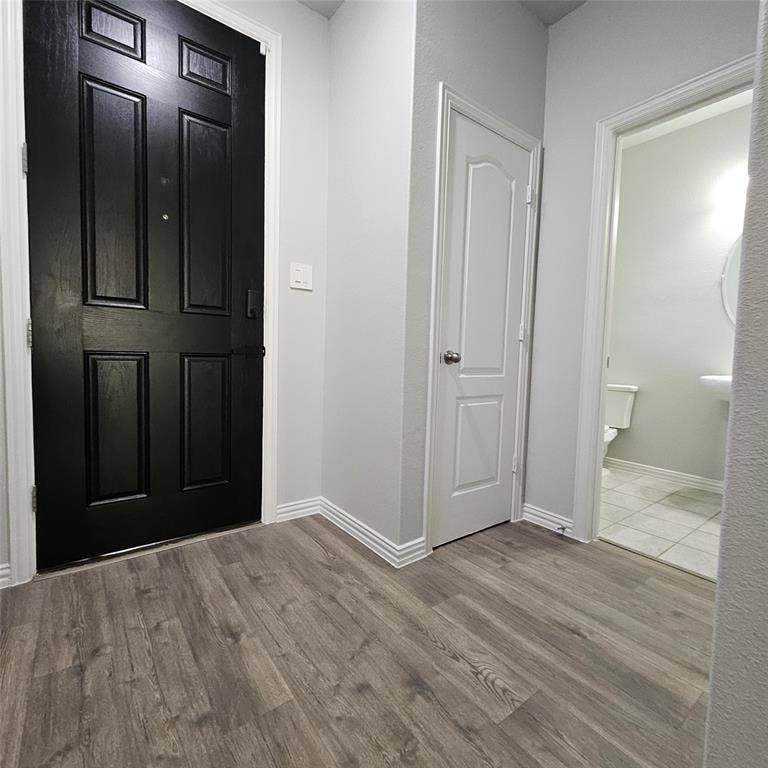 2225 Crooked Bow Drive, Mesquite, TX 75149 Panel-style entry door, wood-finish flooring, paneled interior door, white baseboards, and a pedestal sink in the powder room