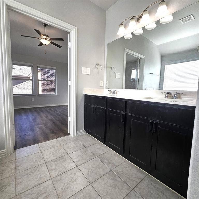 2225 Crooked Bow Drive, Mesquite, TX 75149 Dual vanity with black cabinetry, integrated sinks, chrome faucets, and an expansive mirror