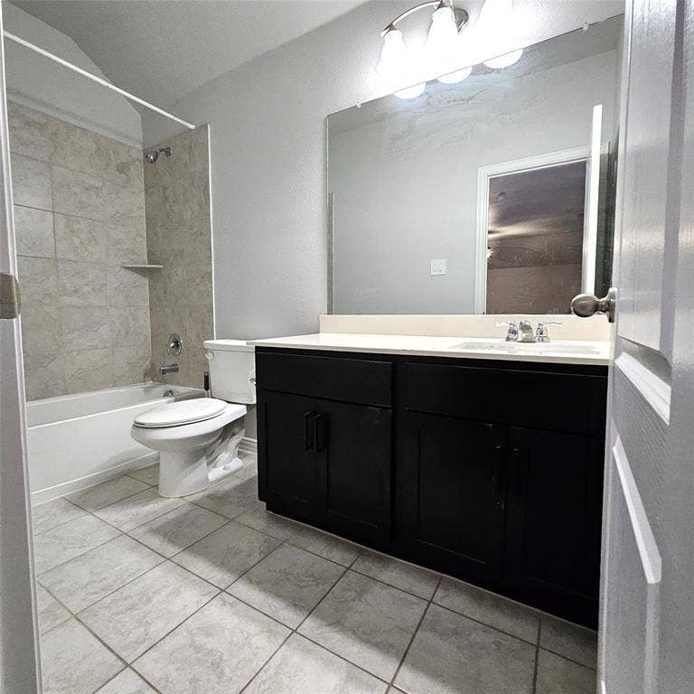 2225 Crooked Bow Drive, Mesquite, TX 75149 Bathroom featuring a vanity with dark cabinetry and light-toned countertop, a large wall-mounted mirror, a tub/shower combination with tiled surround, and tiled flooring