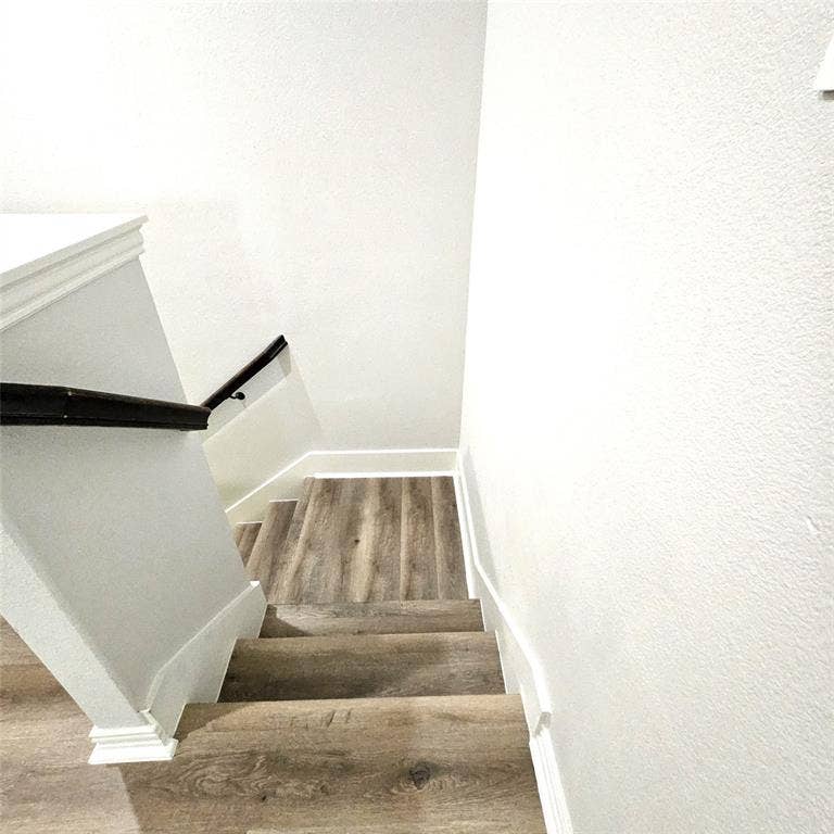 2225 Crooked Bow Drive, Mesquite, TX 75149 Staircase featuring wood-finish flooring, white risers, a dark wood-finish handrail, and white baseboards