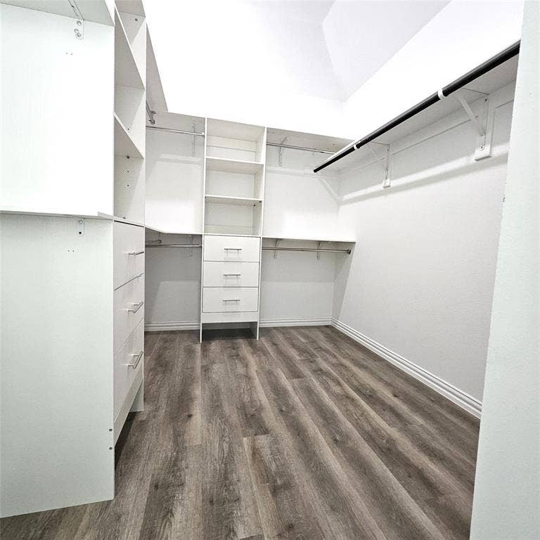 2225 Crooked Bow Drive, Mesquite, TX 75149 Walk-in closet featuring built-in shelving, integrated drawers, multiple hanging rods, and wood-finish flooring