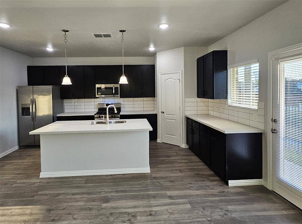 2225 Crooked Bow Drive, Mesquite, TX 75149 Kitchen featuring a center island, stainless steel appliances, dark cabinetry, light countertops, and wood-finish flooring