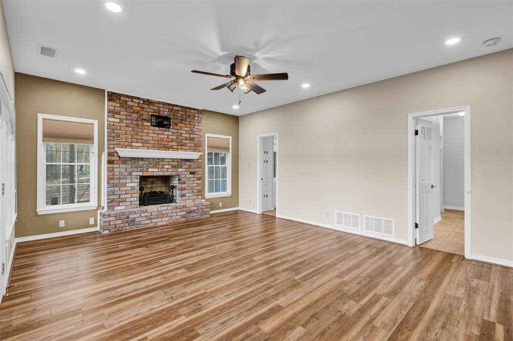 1551 E Tanglewood, Hideaway, TX 75771 Spacious living area featuring wood-finish flooring, a brick fireplace with a white mantel, and recessed lighting