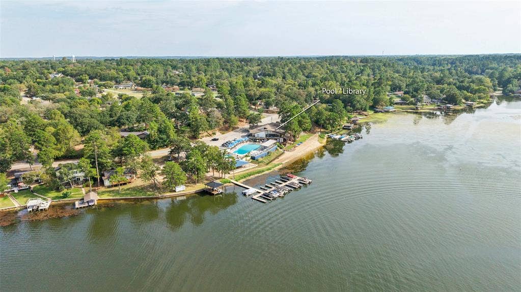 1551 E Tanglewood, Hideaway, TX 75771 Waterfront property featuring extensive tree coverage, a private dock, and an adjacent community pool