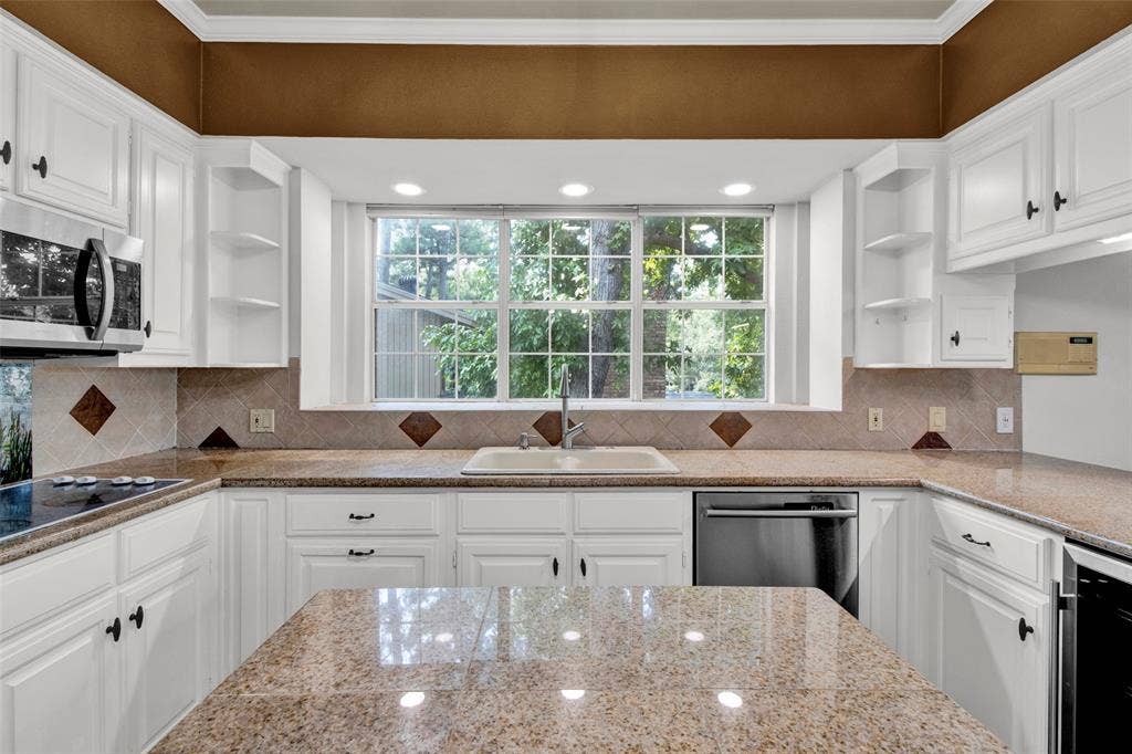 1551 E Tanglewood, Hideaway, TX 75771 White cabinetry with black hardware, granite countertops, and a tiled backsplash with diamond accents
