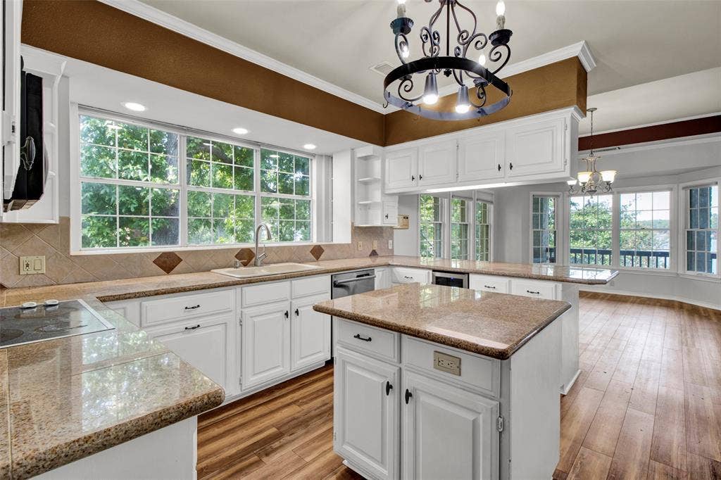 1551 E Tanglewood, Hideaway, TX 75771 White cabinetry, granite countertops, tile backsplash, wood-finish flooring, and an island with additional storage
