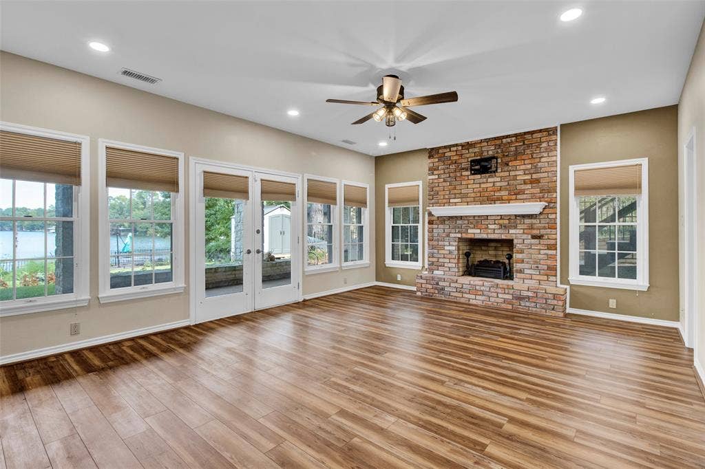1551 E Tanglewood, Hideaway, TX 75771 Wood-finish flooring, brick fireplace with a decorative mantel, ceiling fan, recessed lighting, and multiple windows with cellular shades