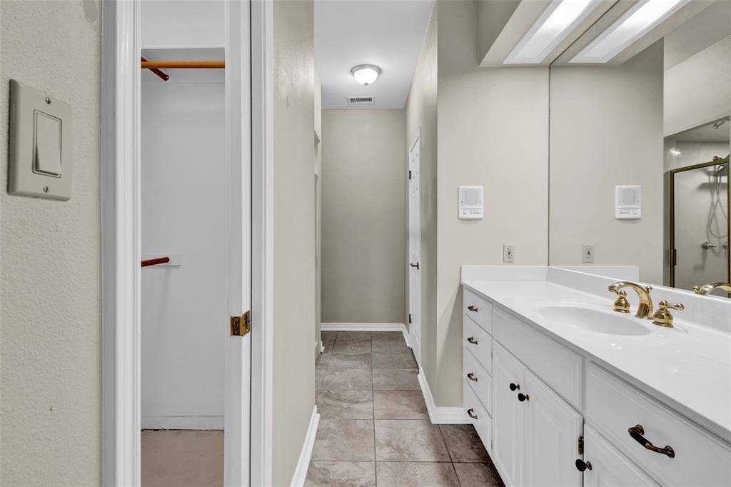 1551 E Tanglewood, Hideaway, TX 75771 Bathroom featuring a single vanity with a white countertop, gold-toned faucet, and a large wall-mounted mirror