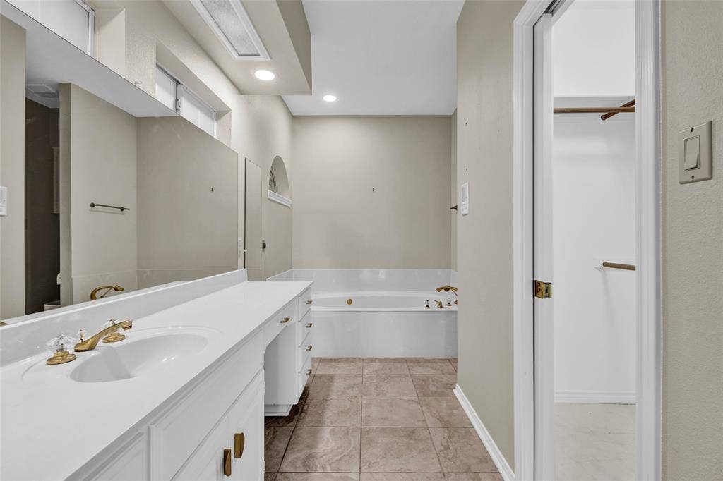 1551 E Tanglewood, Hideaway, TX 75771 Vanity with integrated sink and brass-finish faucet, along with a built-in bathtub