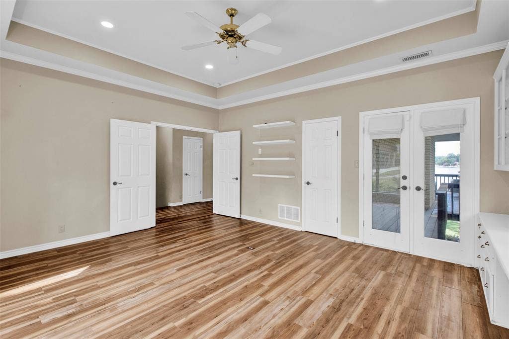 1551 E Tanglewood, Hideaway, TX 75771 Tray ceiling with recessed lighting and a ceiling fan, wood-finish flooring, built-in shelving, built-in cabinetry with a countertop, and glass-paneled French doors