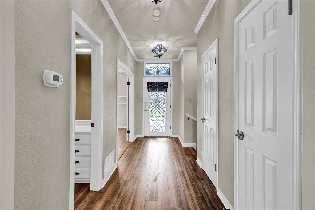 1551 E Tanglewood, Hideaway, TX 75771 Wood-finish flooring extending throughout, crown molding, and a decorative front door with transom window