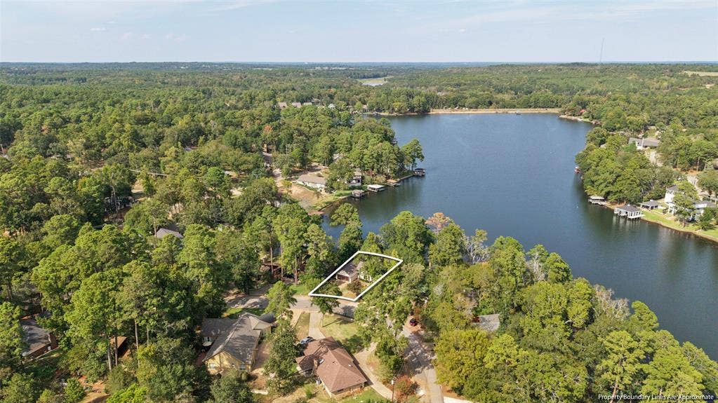 1551 E Tanglewood, Hideaway, TX 75771 Lakeside property bordered by mature trees, featuring a prominent waterfront and surrounding wooded landscape