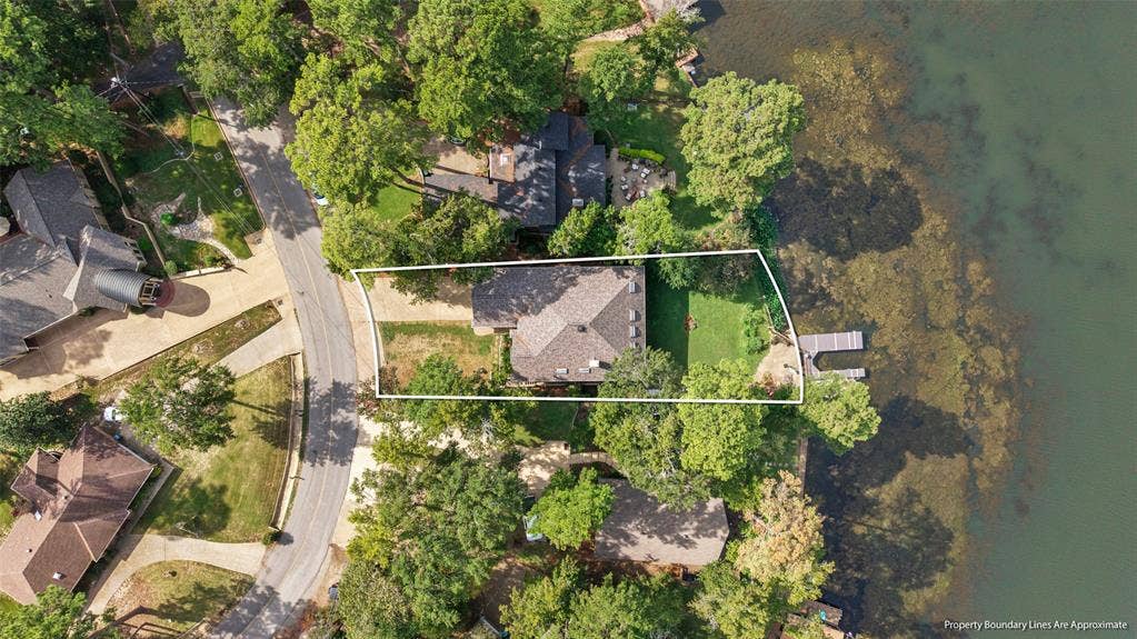 1551 E Tanglewood, Hideaway, TX 75771 Waterfront property with a private dock, expansive green space, mature trees, and a paved driveway