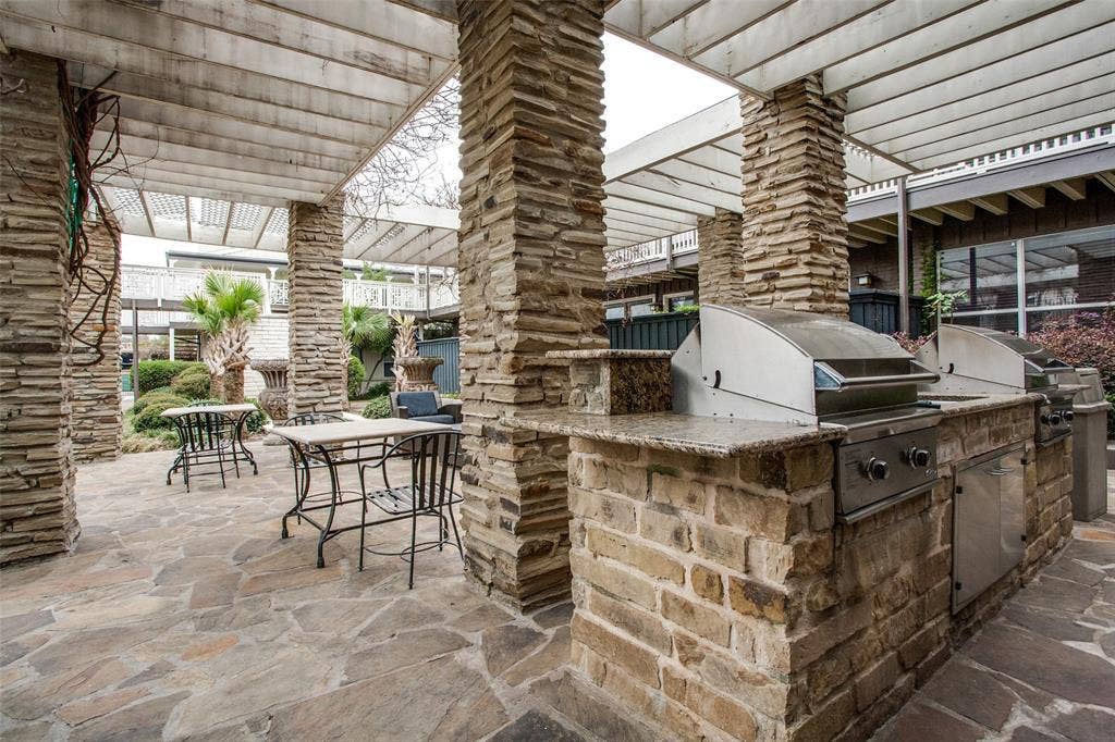 5934 Sandhurst Lane, #208, Dallas, TX 75206 Outdoor entertainment area featuring a stone patio, stone-clad columns, a pergola, and a built-in barbecue station with stainless steel grills and granite-look countertops