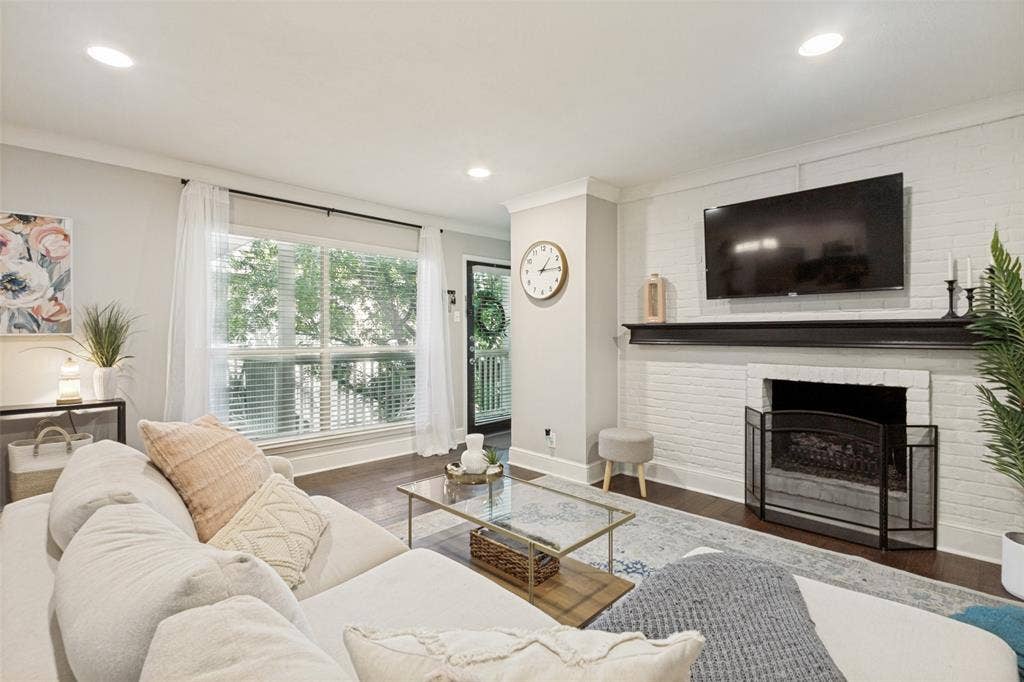 5934 Sandhurst Lane, #208, Dallas, TX 75206 Recessed lighting, wood-finish flooring, white brick fireplace with a dark mantel, large window with blinds, and crown molding