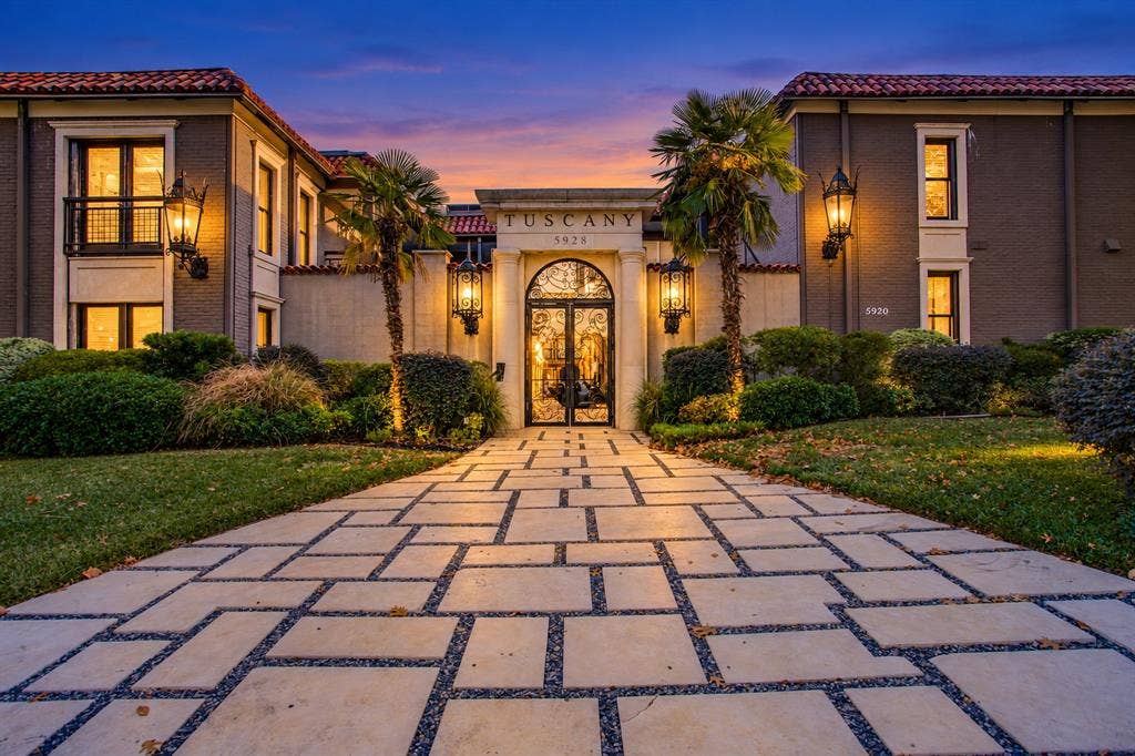 5934 Sandhurst Lane, #208, Dallas, TX 75206 Paver walkway with gravel accents leading to a main entrance featuring an arched doorway, ornate glass and metal doors, and prominent wall sconces