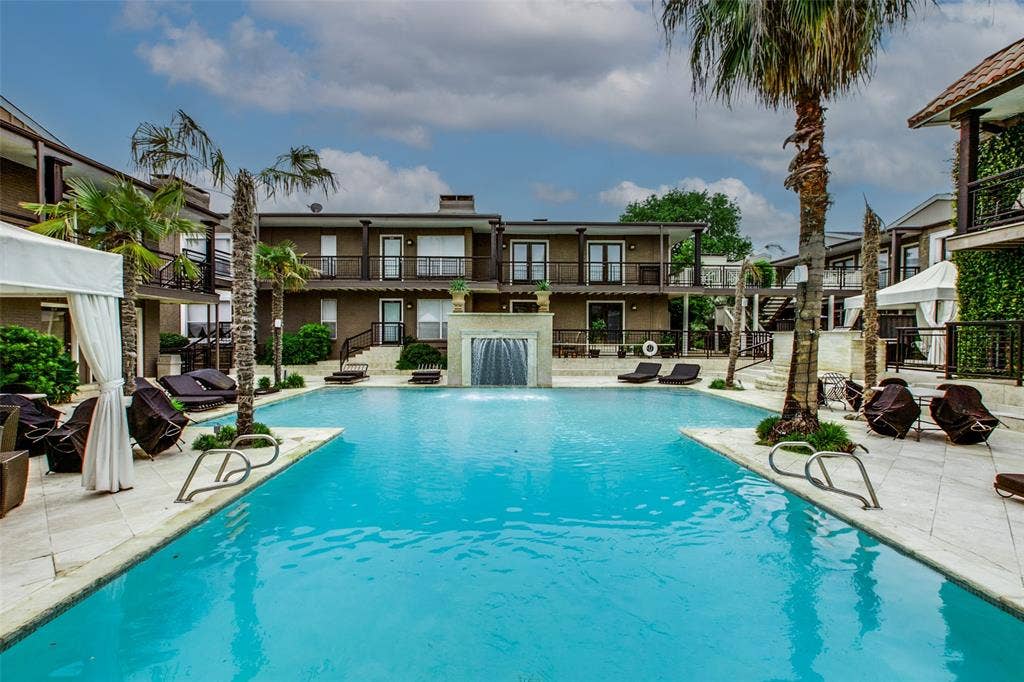 5934 Sandhurst Lane, #208, Dallas, TX 75206 Expansive swimming pool with a central water feature, surrounded by paver decking and mature palm trees