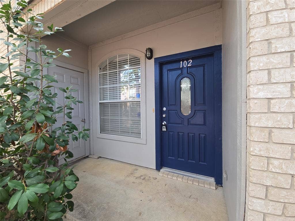 1501 Cedar Elm Drive, #102, Euless, TX 76039 Entryway featuring a paneled door with decorative glass, an arched window with blinds, and light-colored brick siding