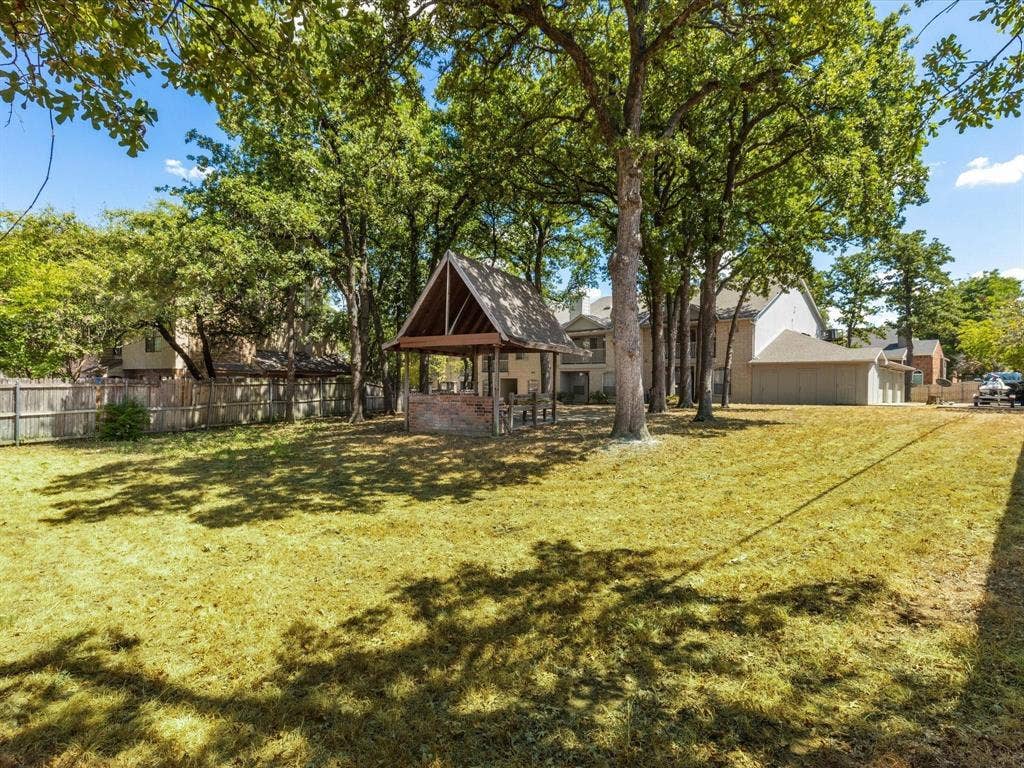 1501 Cedar Elm Drive, #102, Euless, TX 76039 Expansive grassy yard with mature trees, a wood-framed gazebo, and perimeter fencing