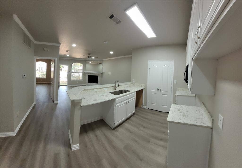 1501 Cedar Elm Drive, #102, Euless, TX 76039 Open-concept kitchen featuring white cabinetry, light-toned countertops, and wood-finish flooring