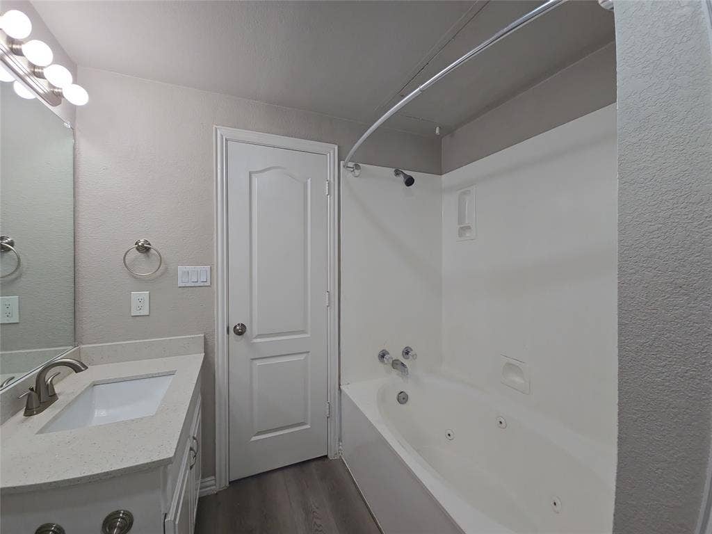 1501 Cedar Elm Drive, #102, Euless, TX 76039 Jetted bathtub with shower, vanity with integrated sink, stone-finish countertop, and wood-finish flooring